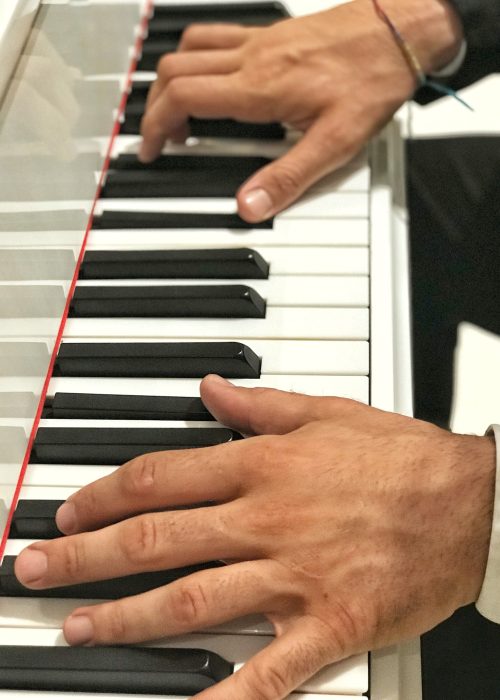Unrecognizable person with large hands and long fingers playing Piano at a social event